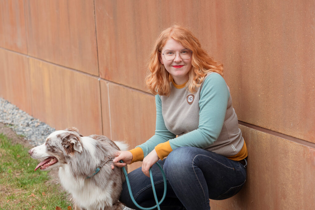 A woman is crouching and holding onto a dog.