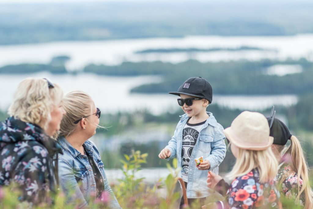 Two women and three children are having a snack break at a scenic viewpoint.